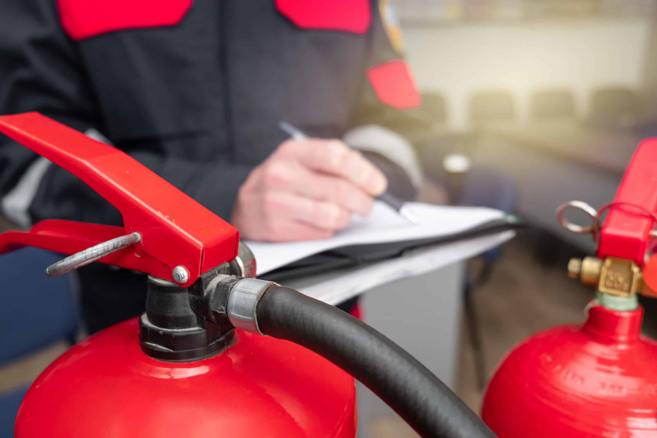 Engineer servicing fire extinguisher and writing his report.